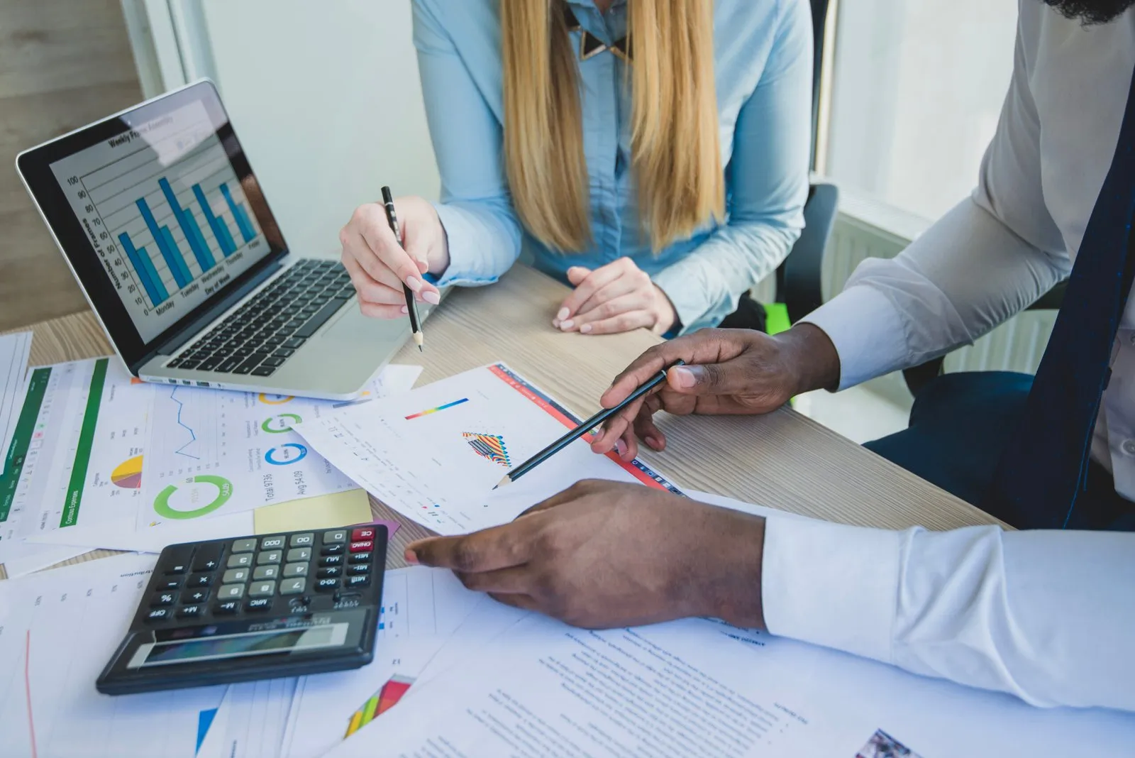 Two advisers reviewing printed financial charts across a desk